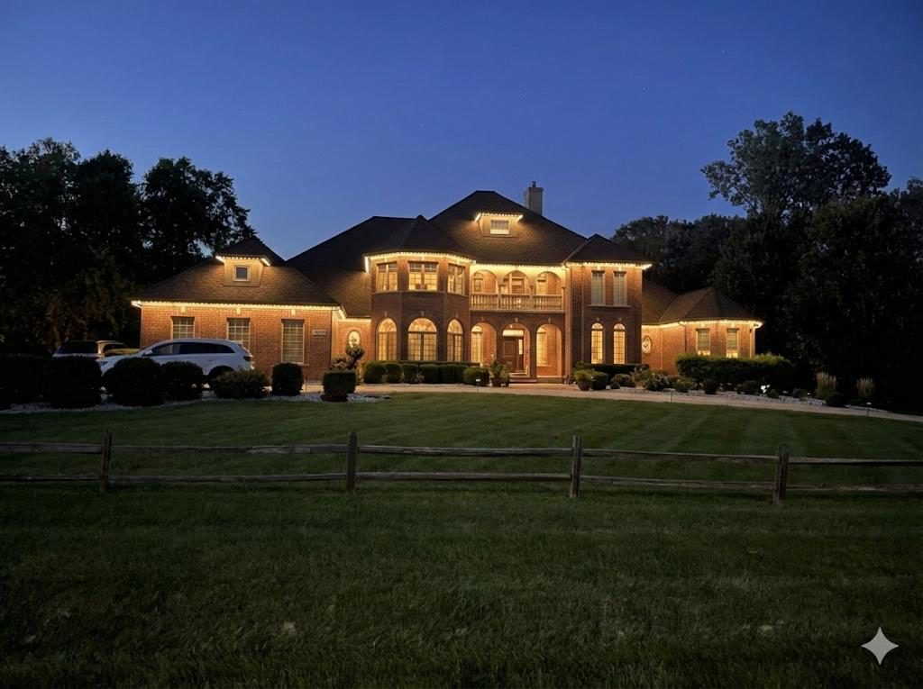 Large brick home with architectural downlighting at dusk