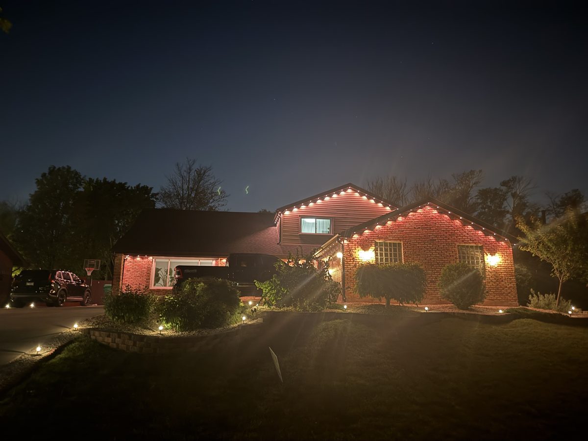 Brick home outlined in warm permanent lighting