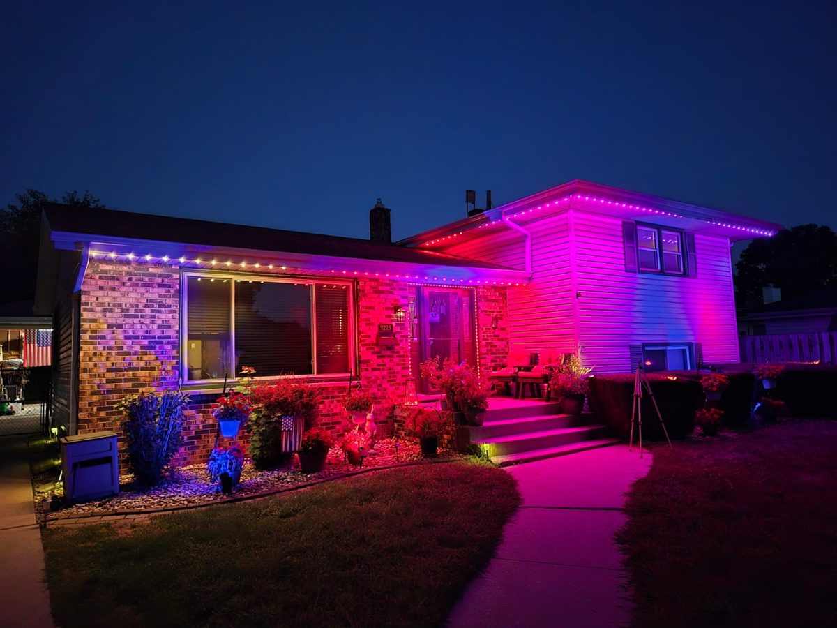 Split-level home lit in pink and purple color-changing permanent lighting at dusk